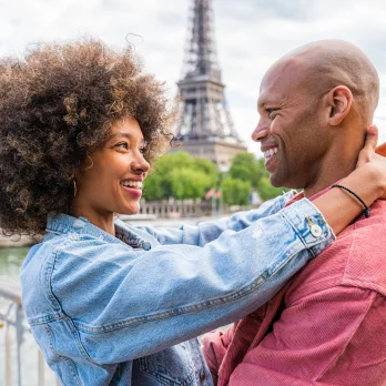 couple devant tour Eiffel apres avoir commander un circuit touristique en arrivant dans un aeroport de Paris